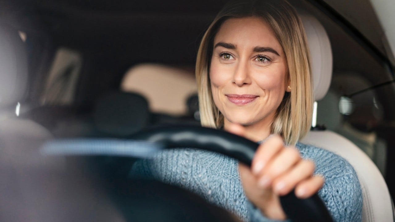 Portrait of smiling young woman driving a car